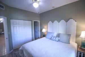a bedroom with a large white bed with blue pillows at Sunsets and Palms in Gulf Shores