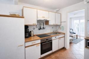 a kitchen with white cabinets and a stove top oven at Ferienhaus Klüver in Kühlungsborn