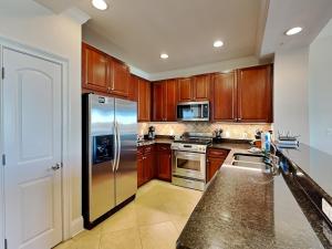 a kitchen with wooden cabinets and a stainless steel refrigerator at Adagio #402D in Santa Rosa Beach +36 photos
