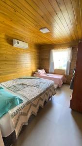 two beds in a room with wooden walls at Chalé beira mar in Prado +15 photos