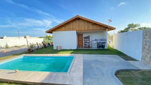 a villa with a pool in front of a house at Chalé beira mar in Prado
