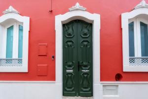 a green door in a red building with two windows at Casa Butterfly in Faro