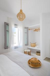 a straw hat sitting on a bed in a white room at Relaxia Estate Naxos By KB Hospitality in Galini