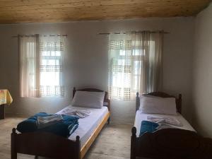 two beds in a room with two windows at Guesthouse Silvester in Gjelaj
