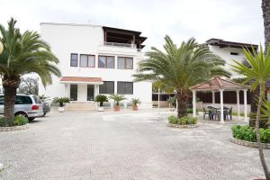 a white building with palm trees in front of it at Villa Erry in Trani