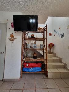a room with a tv on the wall and stairs at Casa de playa El Artesano in Ixtapa