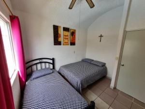 two beds in a room with a cross on the wall at Casa de playa El Artesano in Ixtapa