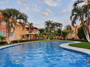 a large swimming pool with palm trees and buildings at Casa de playa El Artesano in Ixtapa