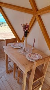 a wooden table with plates and a vase with flowers on it at Dôme géodésique Le petit prince in Le Rousset