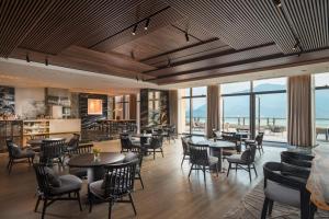 a restaurant with tables and chairs and windows at Conrad Hangzhou Tonglu in Yinzhu