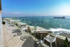 a row of tables and chairs on a balcony with the ocean at Hampton By Hilton Antofagasta in Antofagasta +30 photos