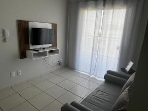 a living room with a flat screen tv and a couch at Apartamento com varanda in Lavras