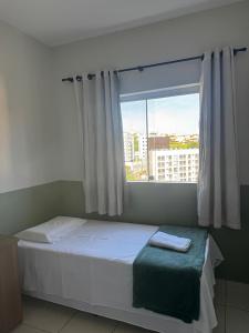 a bed in a room with a large window at Apartamento com varanda in Lavras