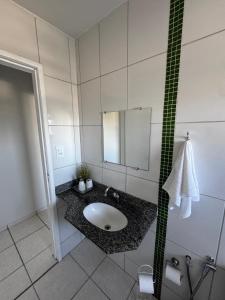 a bathroom with a sink and a mirror at Apartamento com varanda in Lavras +9 photos