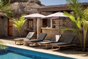 a group of chairs and umbrellas next to a pool at Hotel Boutique Pikiliki - ADULTS ONLY in Brisas de Zicatela