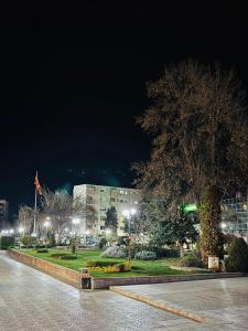 a building with lights in front of a park at night at Zulu Apartments and Studios in Kumanovo +11 photos