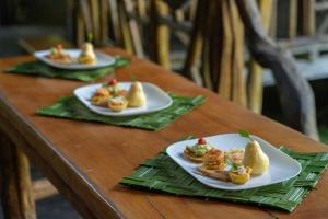 three plates of food on a wooden table at Sinchi Warmi Amazon Lodge in Puerto Misahuallí
