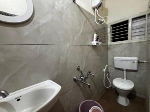 a bathroom with a sink and a toilet and a window at Hazel's ELiTE Homestay 2bhk in Mysore