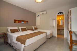a hotel room with two beds and a bathroom at Pousada Jangadeiro in Porto Seguro