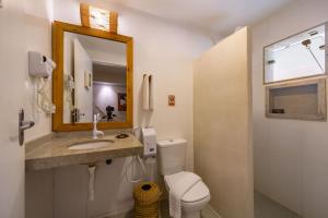 a bathroom with a toilet and a sink and a mirror at Pousada Jangadeiro in Porto Seguro +35 photos