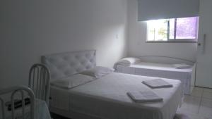 Dieses weiße Zimmer verfügt über 2 Betten und ein Fenster. in der Unterkunft Cabo Frio Flats in Cabo Frio