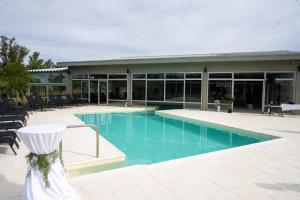 a swimming pool with chairs and a building at Hotel Raices del Arapey in Termas del Arapey