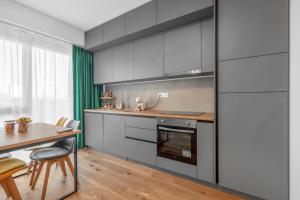 a kitchen with gray cabinets and a table with chairs at XTN Chill House Aeroport with parking in Cluj-Napoca