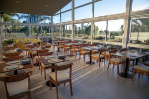 a restaurant with tables and chairs and windows at Hotel Raices del Arapey in Termas del Arapey