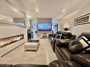 a living room with a leather couch and a fireplace at Skyline Luxury Penthouse Belfast City Centre in Belfast