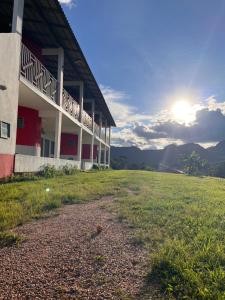 a building with a grass field in front of it at Suítes FM in Cavalcante