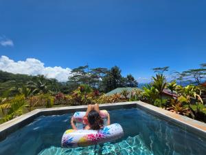 a woman is on an inner tube in a swimming pool at Revatua Lodge Puuru - Piscine privée et Petit-déjeuner inclus in Niumaa