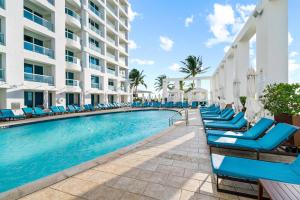 a swimming pool at the resort with blue lounge chairs at Conrad Fort Lauderdale Beach in Fort Lauderdale