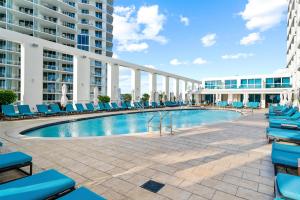 a swimming pool with blue lounge chairs and a building at Conrad Fort Lauderdale Beach in Fort Lauderdale