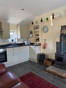 a kitchen with a stove top oven next to a couch at The Stable in Stourton in Stourbridge