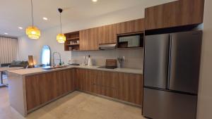 a kitchen with wooden cabinets and a stainless steel refrigerator at Vista Cortes 2BR 2BA Condo - Walk to the Malecon! in La Paz