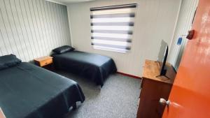 a bedroom with two beds and a desk and a television at Hostal Santa Sabina in Concepción