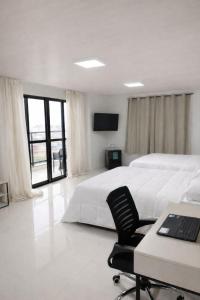 a bedroom with two beds and a desk with a laptop at Miraflores Hotel in Macapá