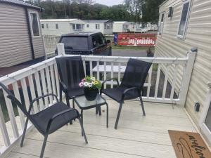 two chairs and a potted plant on a deck at haggerston castle lakeside east 27 in Goswick Station