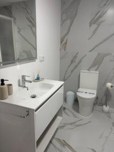 a white bathroom with a sink and a toilet at Casa da Fonte in Rianjo