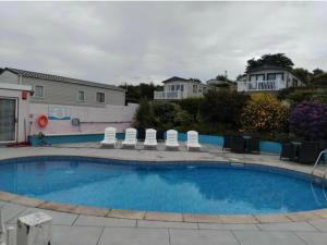 a swimming pool with chairs and a house in the background at 2 Vale Park in Fishguard