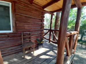 a wooden cabin with a chair on the porch at La Ardilla Chueca in Luján