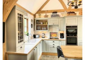 a kitchen with white cabinets and a wooden table at The Saddlery Barn Retreat in Ashford +22 photos