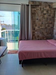 a bedroom with a pink bed and a balcony at Suíte praia de leste in Pontal do Paraná +6 photos
