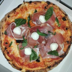 a pizza with ham and cheese on a plate at Appartamento Nivy con posto auto in Bratislava