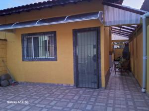 a yellow house with a door and a patio at Casinha marazul in Itanhaém