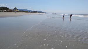 two people standing in the water on the beach at Casinha marazul in Itanhaém