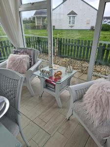 a screened porch with a glass table and chairs at Notre Petit Chateau in Rosslare Harbour