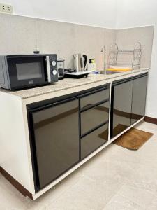 a kitchen counter with a microwave and a sink at Log Cabin Tagaytay in Tagaytay