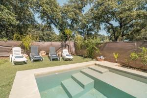 a backyard with a swimming pool with chairs and dogs at Cabaña Rural El Arbol near Setenil - Ronda con piscina in Ronda