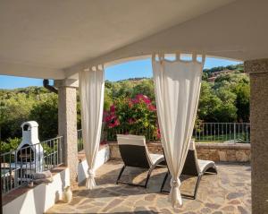 a patio with two chairs and a curtain at International House San Teodoro in San Teodoro